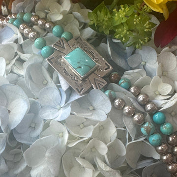 Bracelet with turquoise stones and silver clasp on a floral background