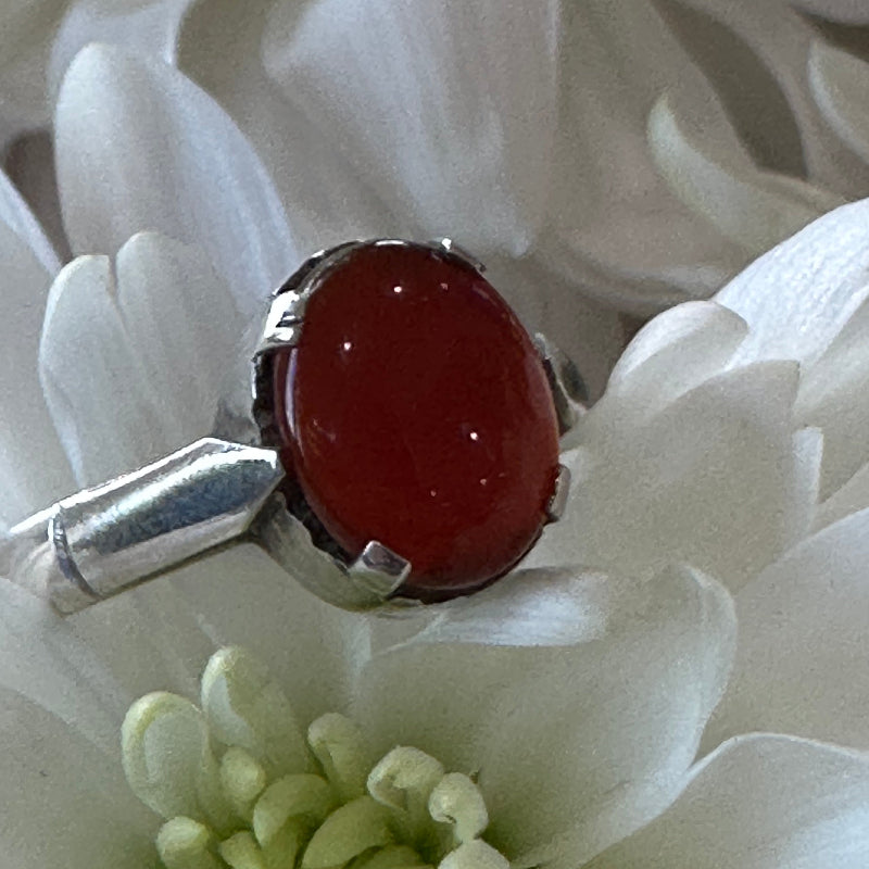 Silver pendant with a red stone on a white flower background