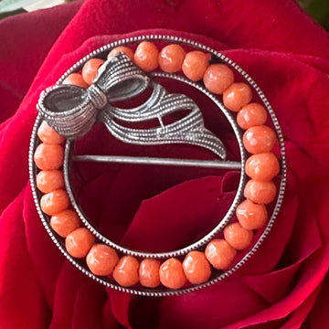 Bracelet with orange beads and silver bow design on a red flower background