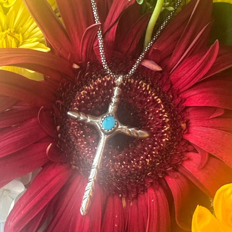 Necklace with a pendant on a red flower with yellow flowers in the background