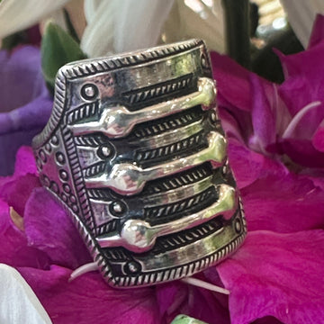 Silver ring with intricate design on a pink flower background
